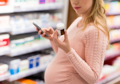 pregnant woman choosing medicine at pharmacy