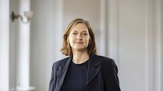 woman in suit jacket in front of white walls