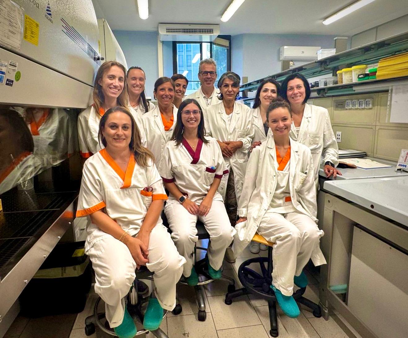 A group of people wearing white medical gowns is smiling at the camera.