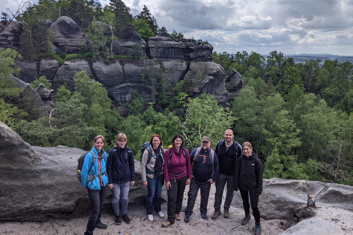 A group of people in hiking overall is smiling at the camera.