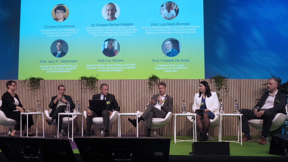 photo of six people on a stage with a brightly lit backdrop