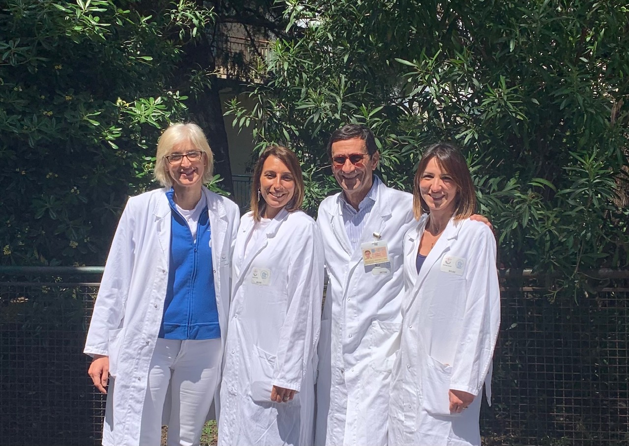 A group of people wearing white medical gowns is smiling at the camera.