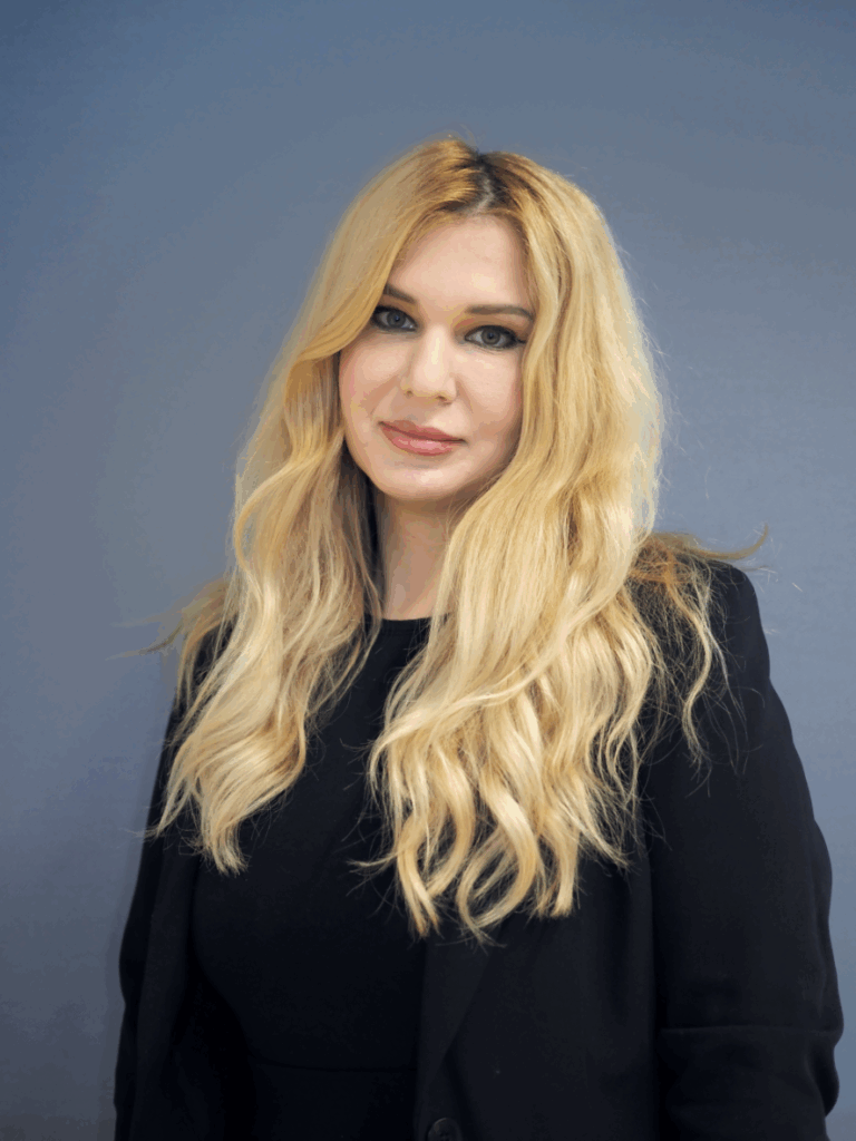 portrait of a white woman with long pale blonde hair who is wearing a black suit